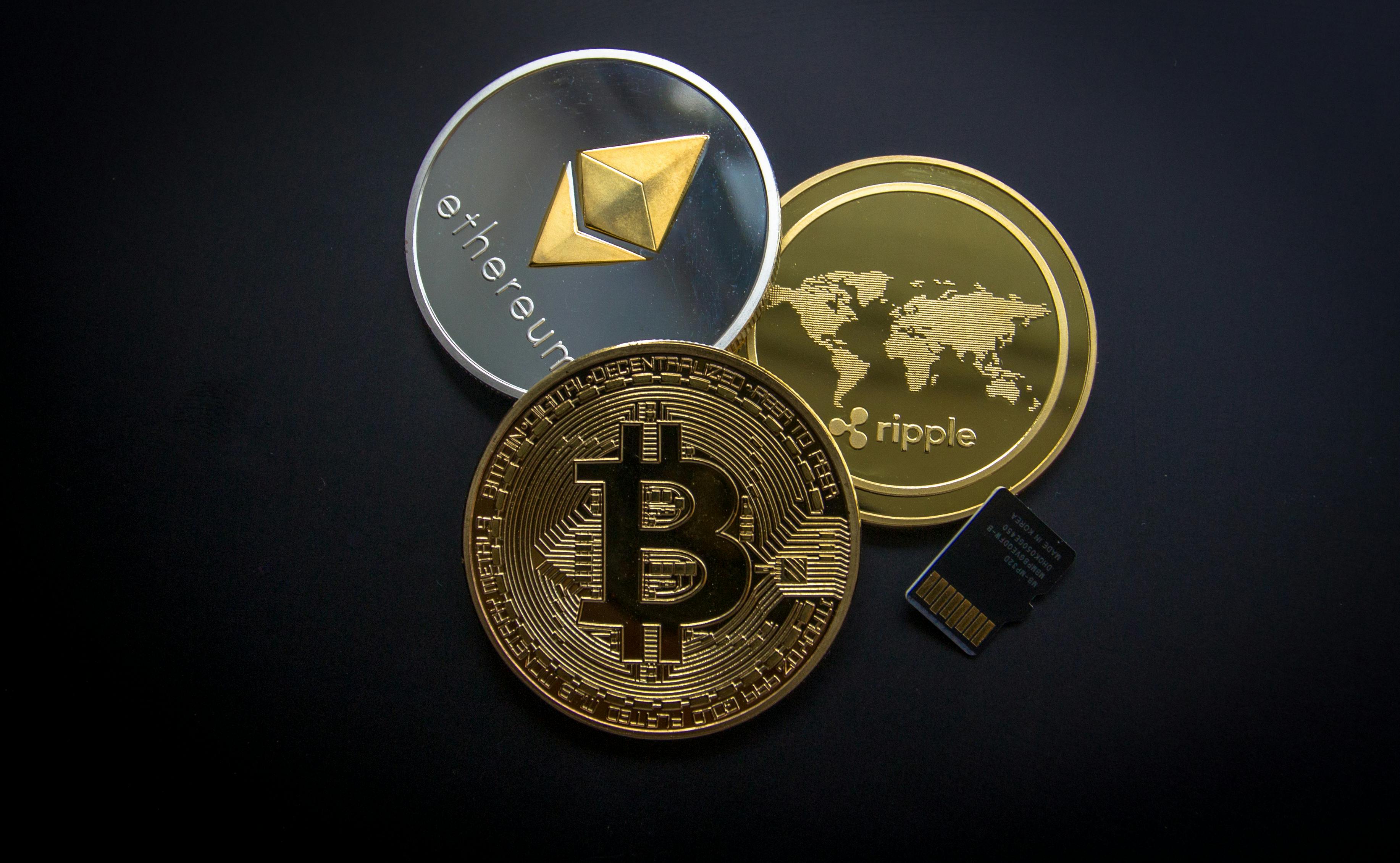 Bitcoin, Ethereum, and Ripple coins with a microSD card on a dark background, representing digital assets and daily trading cryptocurrency.